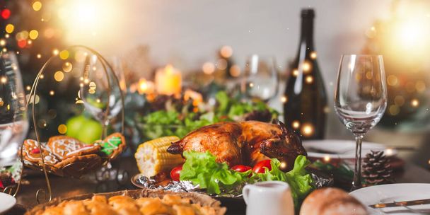 Traditional celebration. Roasted chicken, wine, vegetables salad and various food are set on table for family to celebrate together at night and Christmas tree set in the room for Christmas holiday. - Фото, зображення