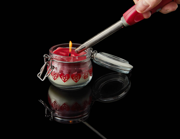 Lighting candle on black background with aromas of vanilla, cherry, pomegranate and coconut. - Photo, Image