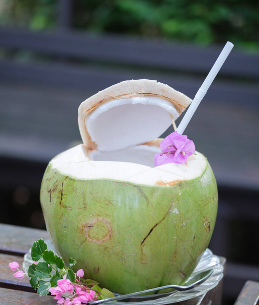 zelená kokosová voda s pitnou slámou na stole - Fotografie, Obrázek