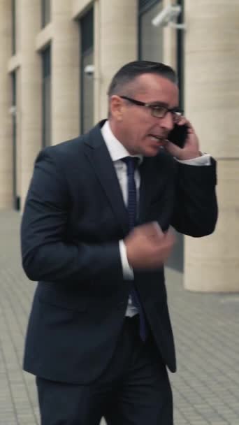 Nervous businessman talking on the phone. He yelling at his opponent with fury. Vertical video - Footage, Video