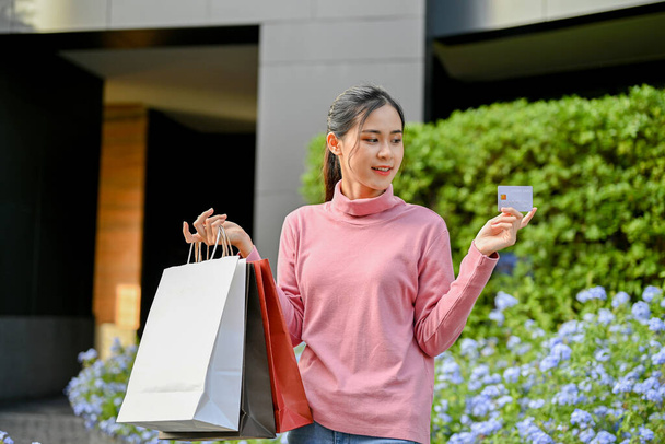 Giovane bella donna in possesso di carta di credito e portando borse della spesa. Stile di vita urbano concetto - Foto, immagini