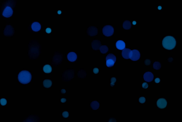 Azul abstracto borrosa bokeh de luces de Navidad sobre fondo negro aislado. Concepto de vacaciones, superposición para sus imágenes. - Foto, imagen