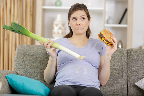 unhappy pregnant woman chooses veggetables to burger - Foto, immagini