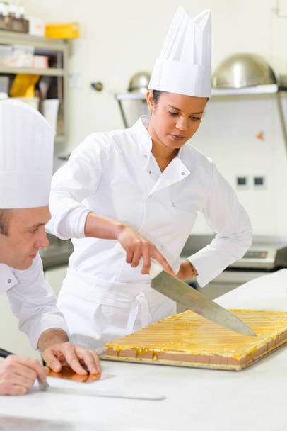 pastry chef intern slicing a cake - 写真・画像