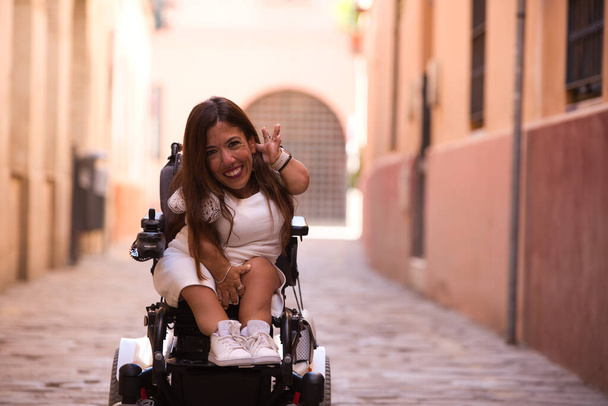 mooie jonge gehandicapte vrouw in rolstoel en beperkte mobiliteit geniet van haar reis door de stad waar ze op vakantie is. - Foto, afbeelding