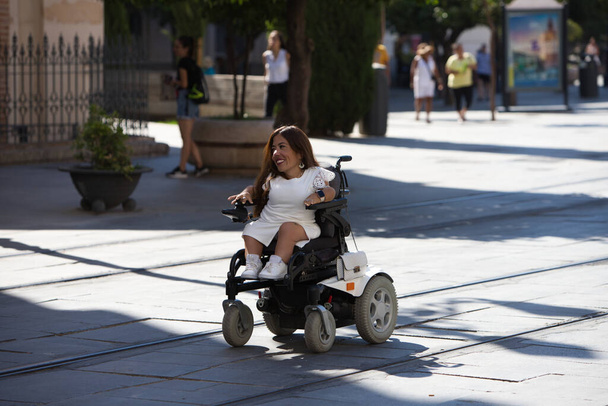 bela jovem deficiente mulher em cadeira de rodas e mobilidade reduzida goza de sua viagem ao redor da cidade onde ela está de férias. - Foto, Imagem