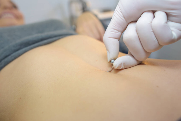 woman getting a belly piercing done - Photo, Image