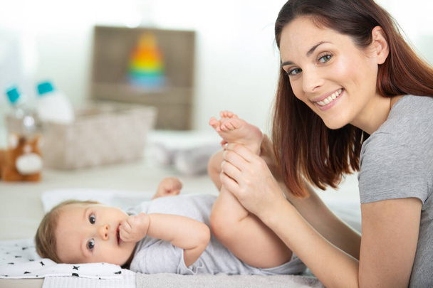 happy mother changing diaper of adorable baby - Fotografie, Obrázek