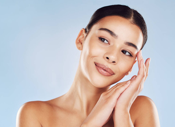 Closeup face beautiful young mixed race woman. An attractive female posing in studio isolated against a blue background. A skincare regime that keeps your skin soft, smooth, glowing and healthy. - Photo, Image