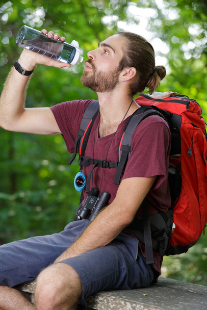 hiking man pouring water from thermos during hot summer day - Fotó, kép