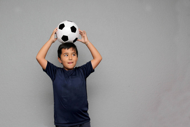 Latino Hispano niño de 8 años juega con una pelota de fútbol muy emocionado de que va a ver el partido de fútbol y quiere ver a su equipo ganar - Foto, Imagen