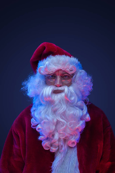 Portrait de Père Noël claus avec des lunettes posant sur fond sombre. - Photo, image