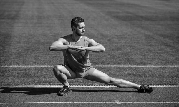 Athletic runner doing stretching exercise preparing for morning workout, warming up. - Valokuva, kuva