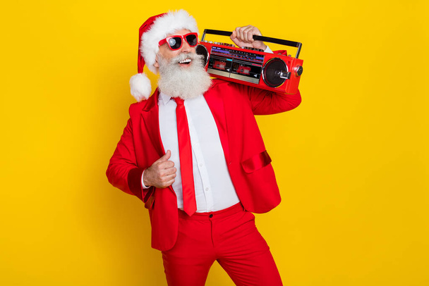 Portrait of positive overjoyed aged person carry boombox enjoy newyear occasion isolated on yellow color background. - Φωτογραφία, εικόνα