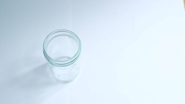 frasco de vidrio con líquido blanco sobre un fondo azul - Foto, Imagen