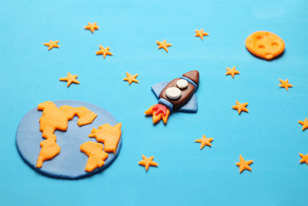 Creative craft plasticine rocket in open space, astronaut dreams. Stars, planet earth and moon. Cartoon art. - Photo, image
