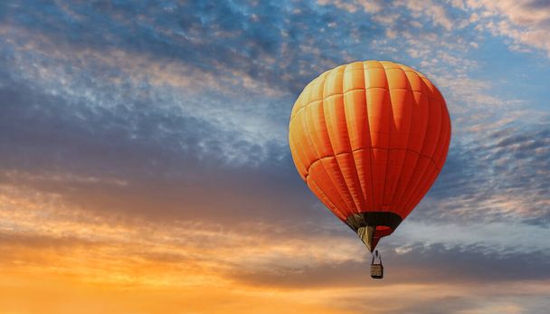 Orange hot air balloon against the backdrop of an expressive sunset sky - Foto, afbeelding