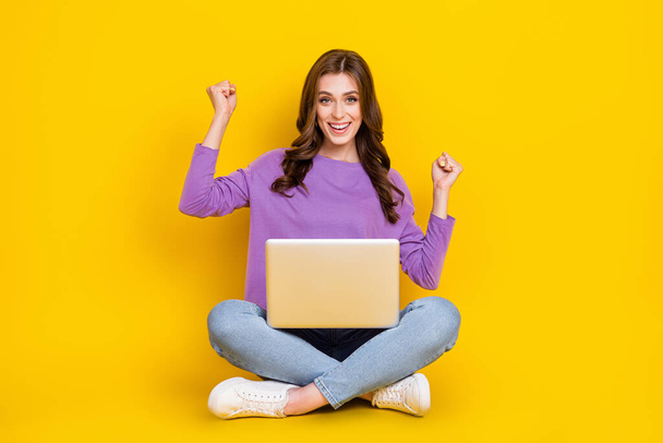 Full size portrait of delighted astonished girl raise fists use wireless netbook isolated on yellow color background. - Foto, Imagen