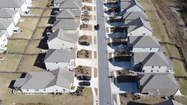 Flying over a HOA neighborhood residential streets parked car and front garage homes in new development subdivision outside Atlanta, Georgia, US. Two story houses well trimmed lawn large backyard - Séquence, vidéo