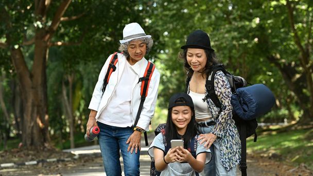 Feliz de mediana edad las mujeres y la chica asiática tomando selfie en el teléfono inteligente, mientras que caminar en verde parque de la ciudad. - Foto, Imagen