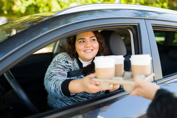 Schöne lateinisch fettleibige Frau, die ihr Auto auf einer Fahrt durch den Kauf von Kaffee to go fährt - Foto, Bild