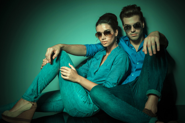 pareja de moda sentado y apoyado en una pared
 - Foto, Imagen