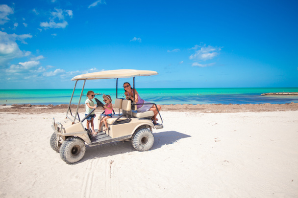 Kleine Mädchen und ihre Mutter fahren Golfcart am tropischen Strand - Foto, Bild