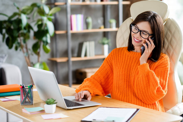 Photo of happy positive lady dressed orange pullover having online interview modern gadget smiling indoors workplace workstation. - Foto, Imagen
