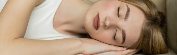 Mujer joven y rubia con los ojos cerrados durmiendo en el sofá en casa, pancarta  - Foto, Imagen