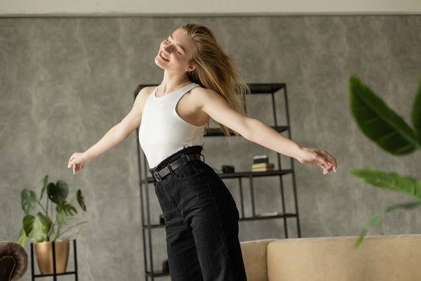 cheerful blonde woman dancing with closed eyes while having fun at home - Fotografie, Obrázek