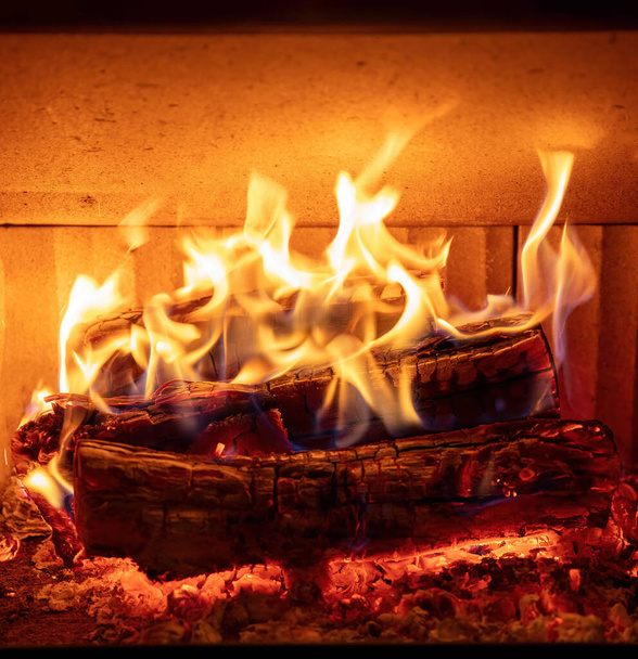 Open haard close-up, vlam van vuur en brandende houtblokken, warm huis in de winter, vooraanzicht - Foto, afbeelding