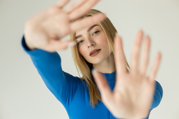 woman with blurred outstretched hands looking at camera isolated on grey - Photo, Image