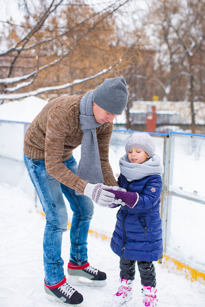 Schattig klein meisje en blij vader op ijsbaan buiten - Foto, afbeelding
