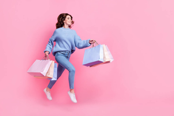Full body profile portrait of overjoyed cheerful lady hold packages jump rush empty space isolated on pink color background. - Φωτογραφία, εικόνα