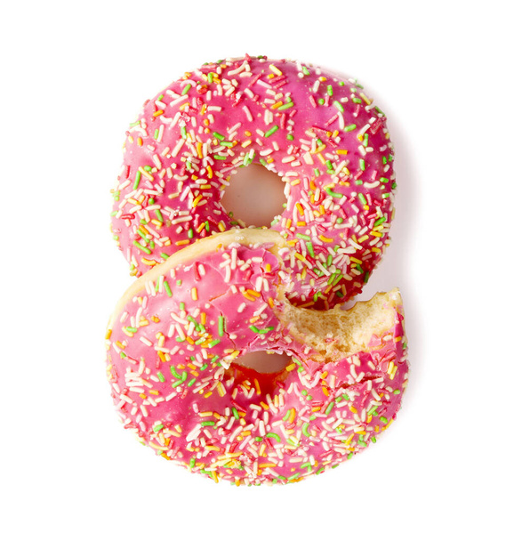 Flat lay of two donuts decorated with colorful sprinkles isolated on white background. Bitten donut - 写真・画像