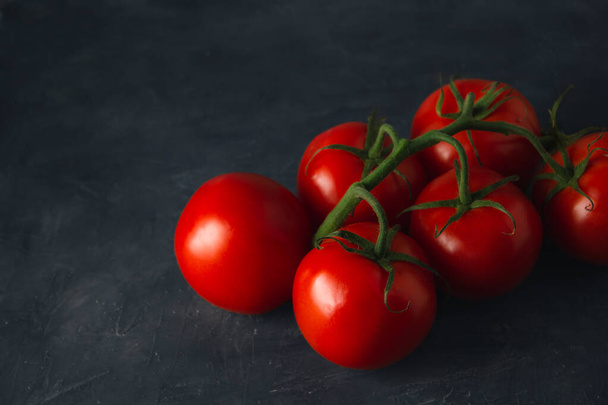 Hochwinkelaufnahme von roten reifen Tomaten auf dunklem Hintergrund. Frische Tomaten dunkle Szene mit Kopierraum. - Foto, Bild