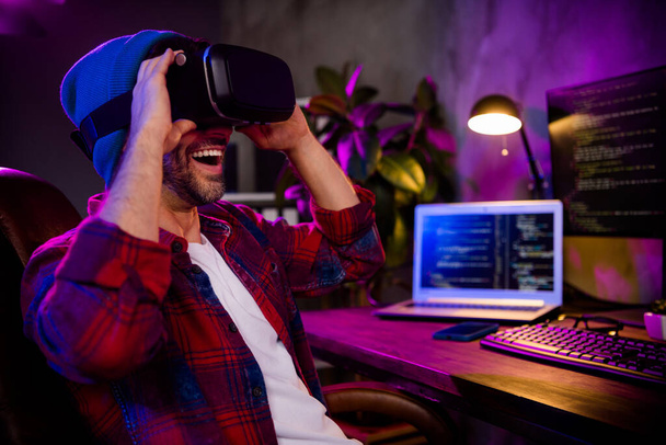 Photo of excited happy guy dressed glasses hat trying new video game modern device indoors workstation workshop home. - Foto, imagen