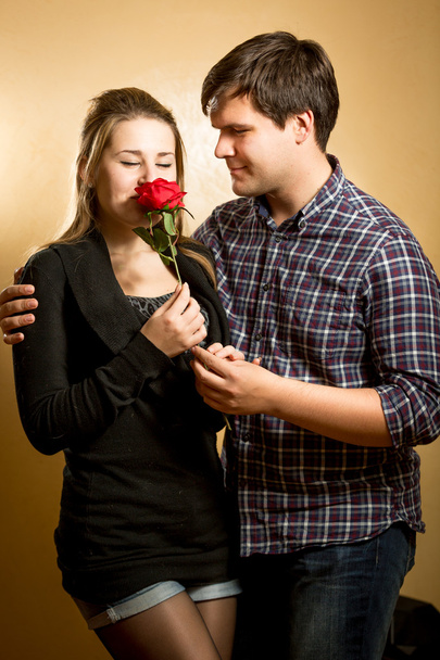 young woman smelling red rose presented by young man - Zdjęcie, obraz