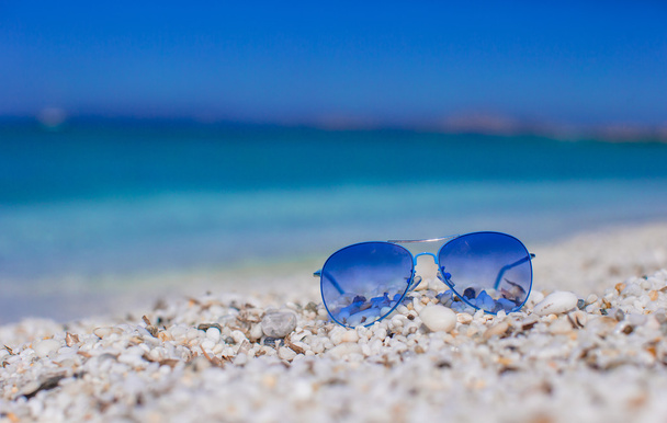 Close up de óculos de sol azuis coloridos na praia tropical
 - Foto, Imagem