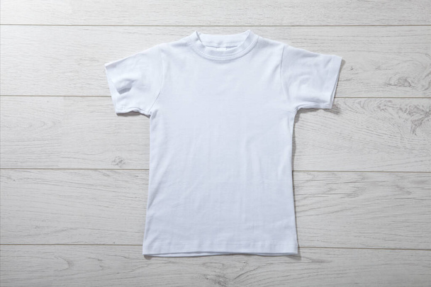 Front views on boys t-shirts on white wooden desk background. Mockup for design close up - Zdjęcie, obraz