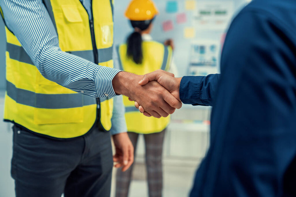 After concluding the meeting, competent investor shakes hands with engineer. Concept of the agreement between engineers and investors. - Φωτογραφία, εικόνα