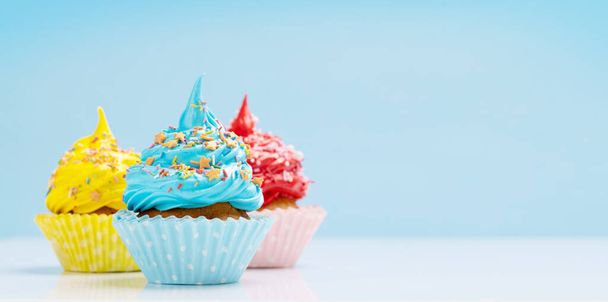 Красочные кексы на синем фоне с копировальным пространством - Фото, изображение