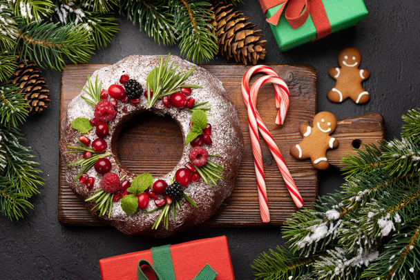 Joulukakku koristeltu granaattiomenan siemeniä, karpaloita ja rosmariinia. Litteä - Valokuva, kuva