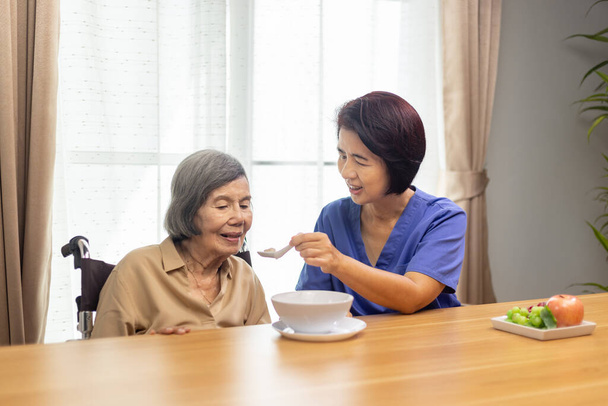 Bakıcı, yaşlı Asyalı kadını çorbayla besliyor.. - Fotoğraf, Görsel