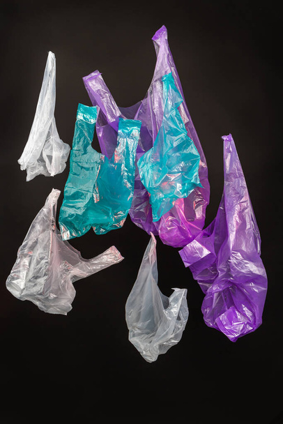 Colección de tiro vertical de coloridas bolsas de plástico. Aislado sobre fondo negro. - Foto, imagen