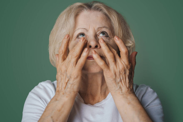 Muotokuva melko vanhempi nainen hydrogeeli silmien alla laikkuja aamulla, joka osoittaa vaikutus täydellinen iho, eristetty vihreällä pohjalla. Anti ikääntyminen - Valokuva, kuva