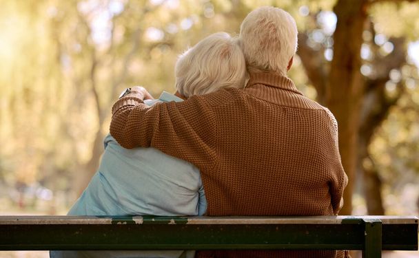 Relax, hug and love with old couple in park for happiness, marriage and calm. Peace, nature and retirement with man embracing woman on bench for affectionate, bonding and wellness date together. - Photo, Image