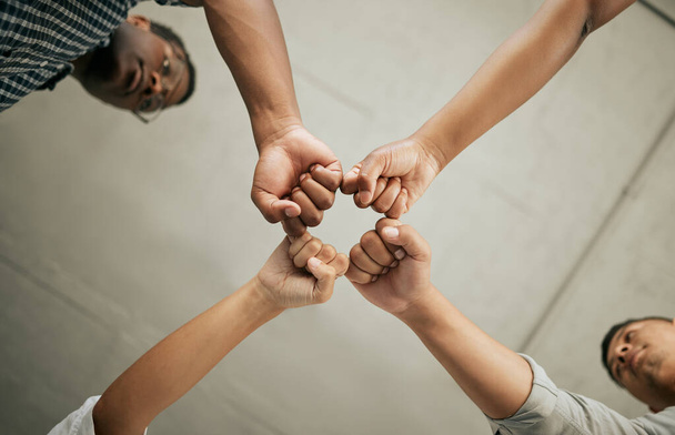 Крупним планом творчі бізнесмени об'єднують свої кулаки знизу. Різноманітна група бізнесменів, що стоять разом в тулубі, демонструючи силу в єдності
. - Фото, зображення