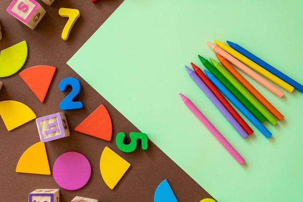 Wooden kids toys on colourful paper. Educational toys, blocks, pyramid, pencils, numbers, rainbow. Toys for kindergarten, preschool or daycare. Copy space for text. Top view. Back to school background - Photo, Image