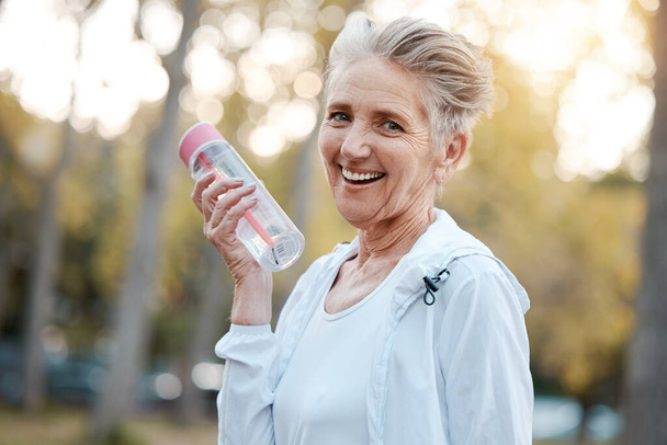 Exercise, senior woman and water bottle for fitness, workout in nature or portrait. Mature female, elderly lady and hydration for wellness, health and training outdoor for cardio, retirement or relax. - Photo, Image